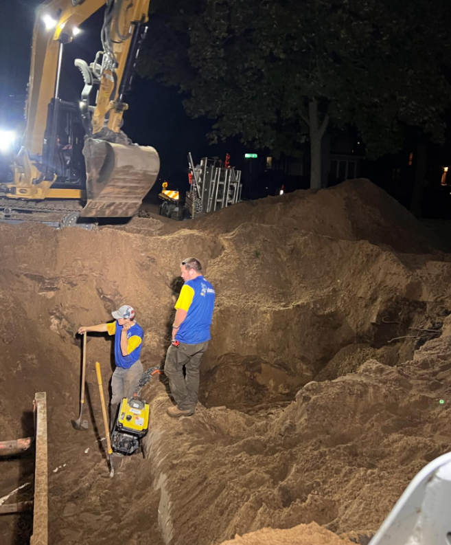 A man in a blue shirt is standing in a pile of dirt