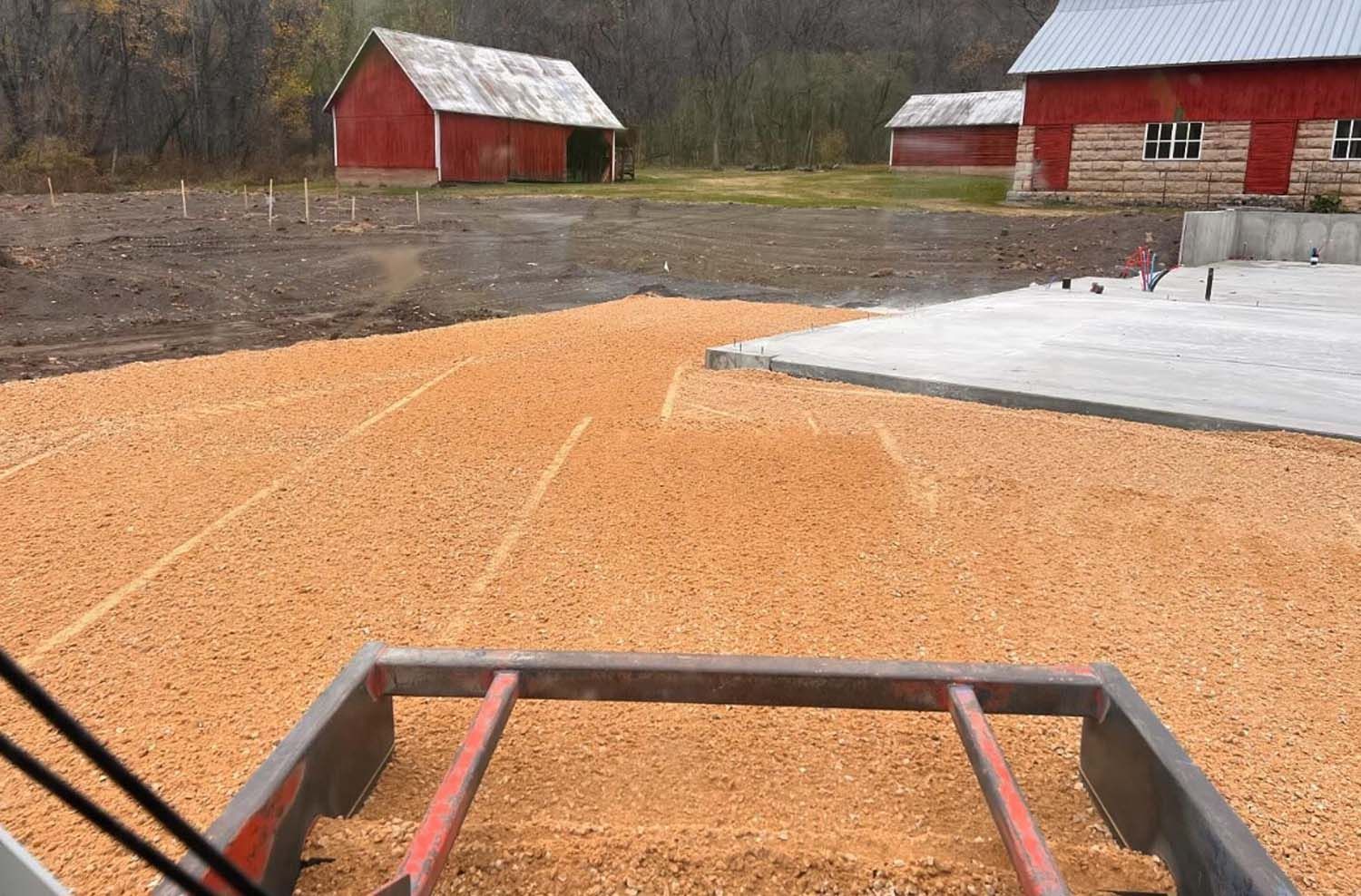A large pile of wood chips is sitting in front of a barn.