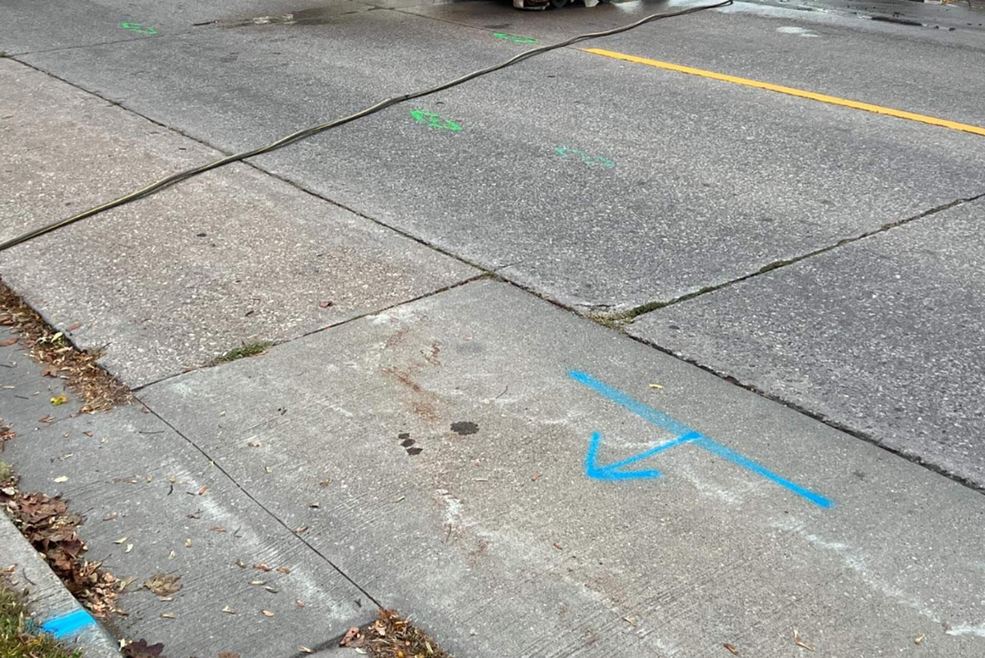 A blue arrow is painted on the sidewalk next to the road