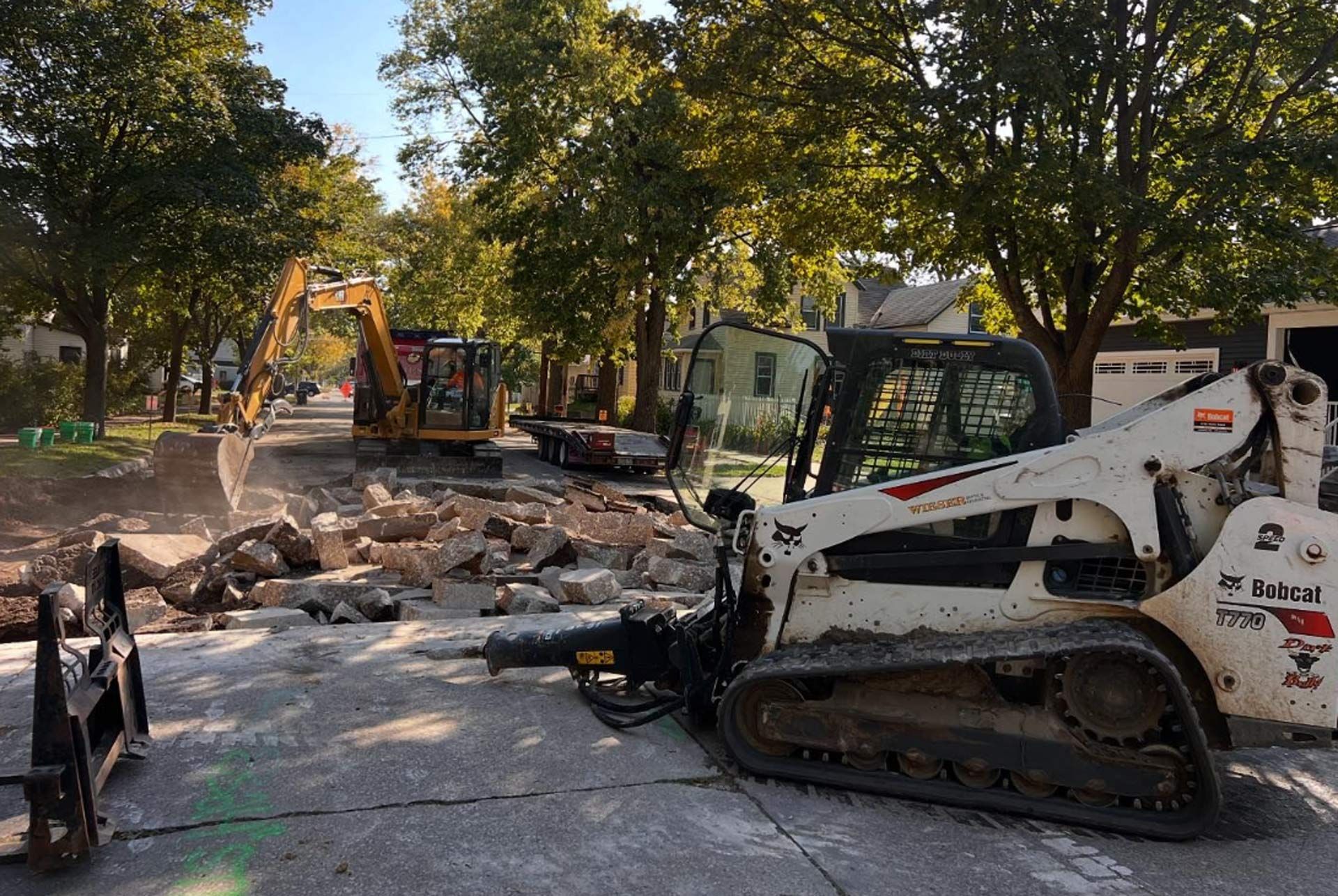 A bobcat is sitting on the side of the road next to a bulldozer