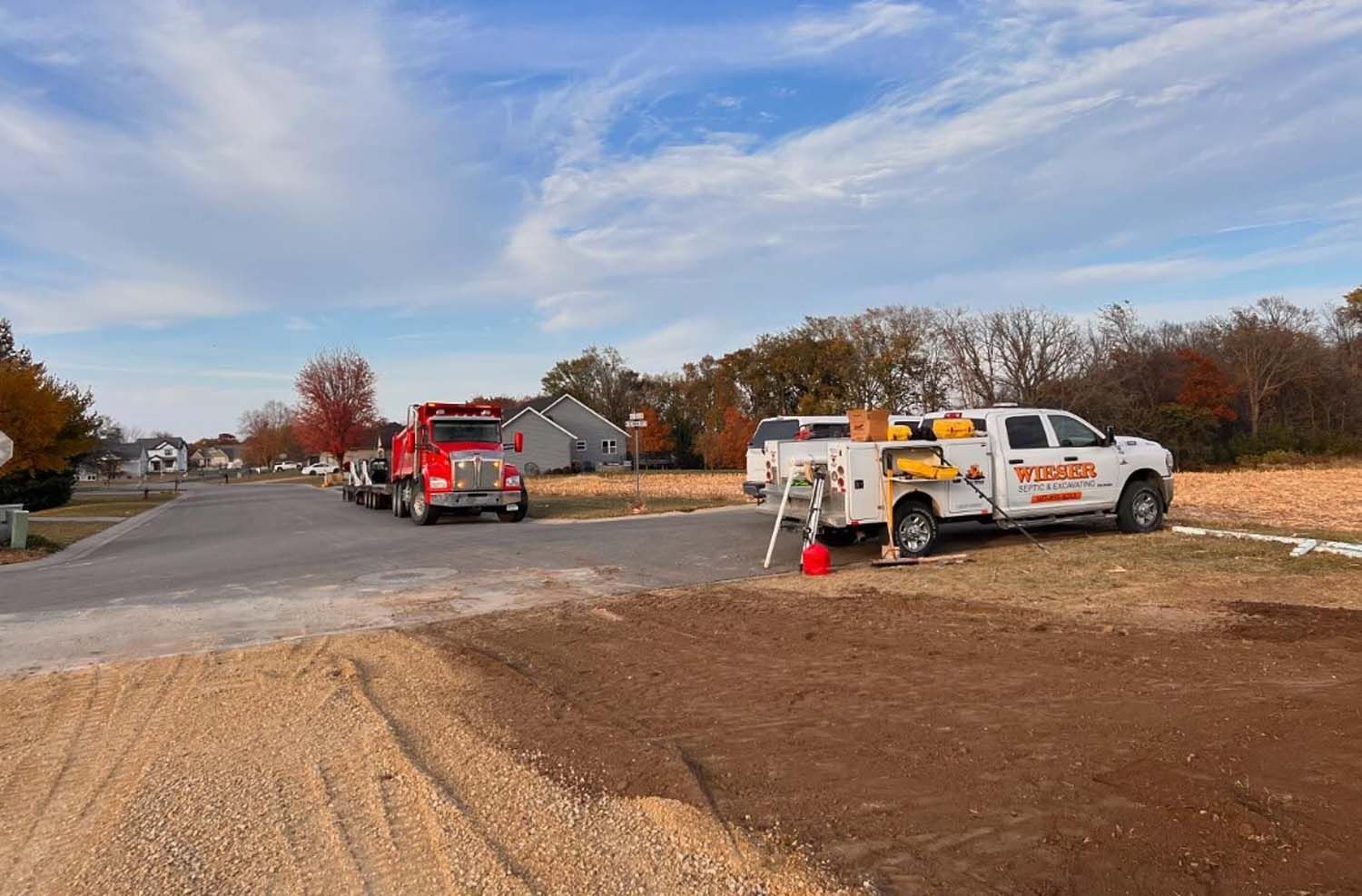 A white truck is parked on the side of the road next to a red truck.