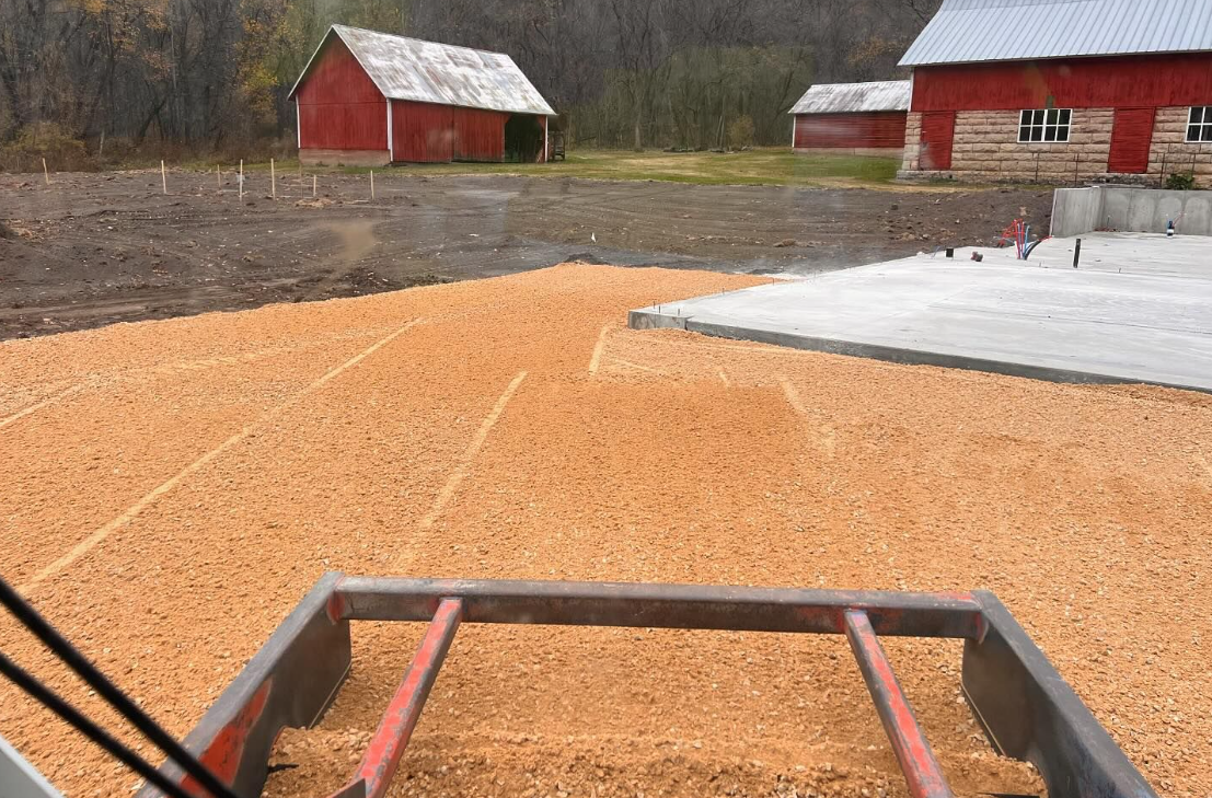 A pile of wood chips is sitting in front of a barn.