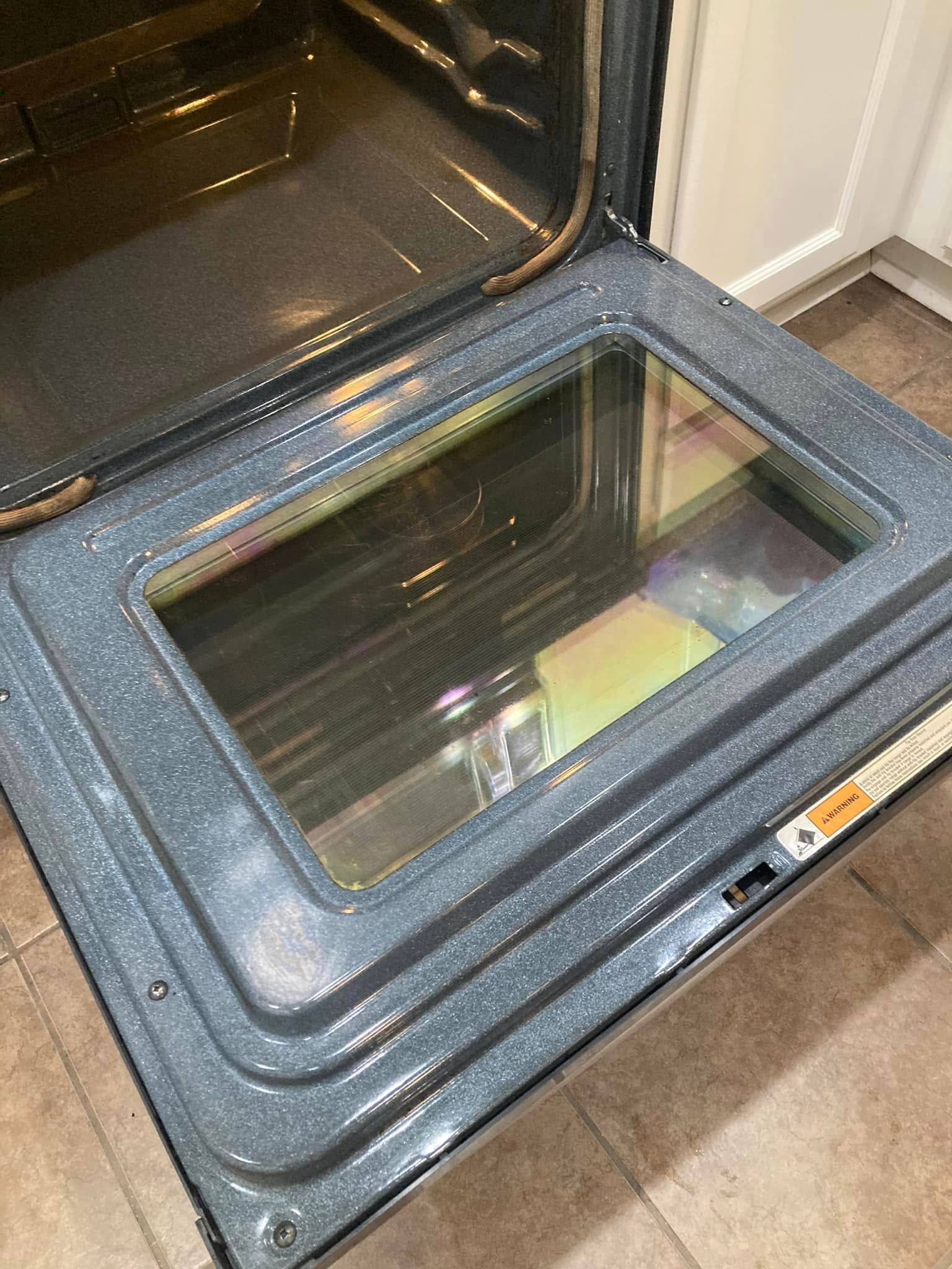 Opened oven door, with a glass window and speckled gray interior.