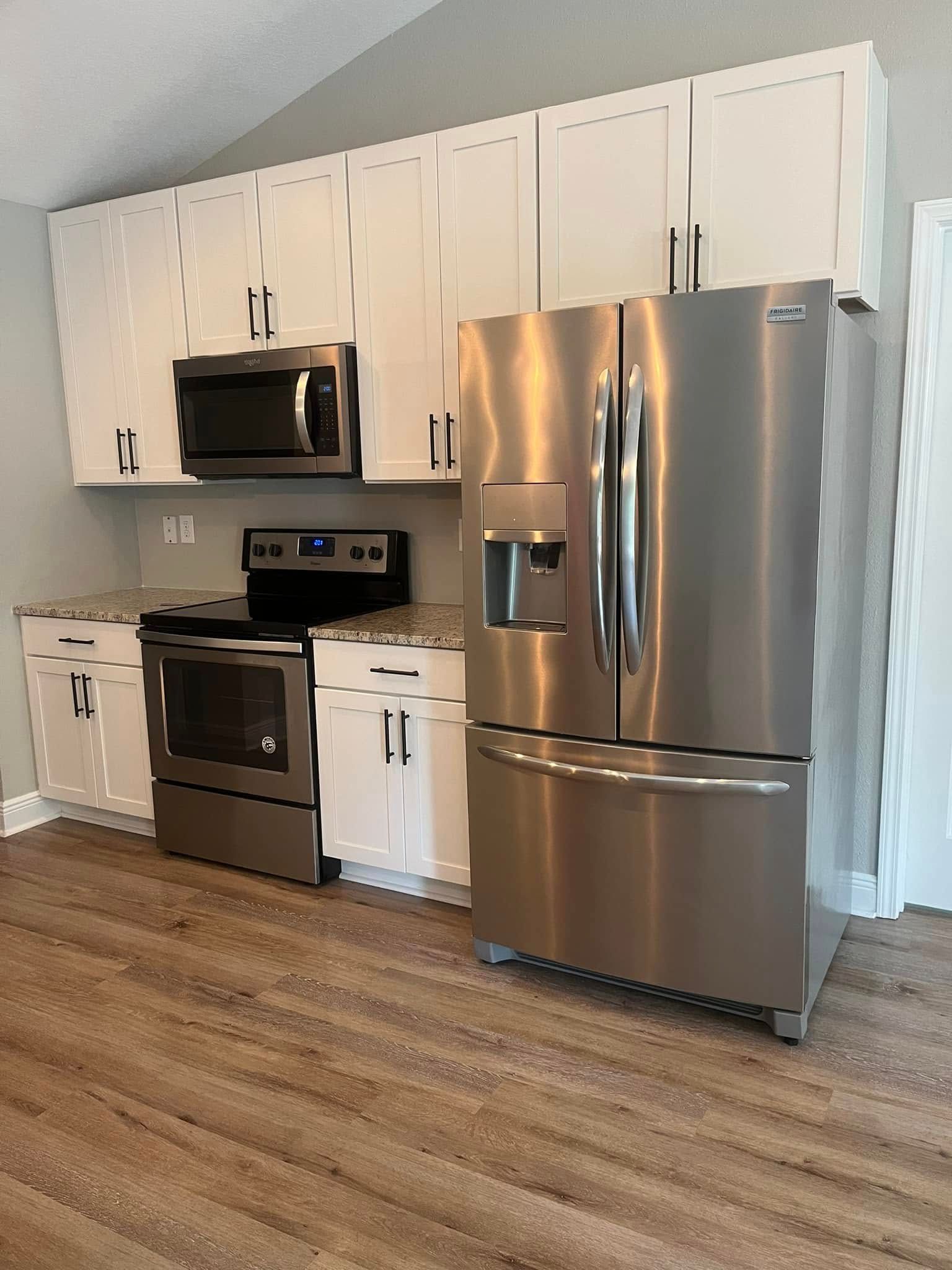 White kitchen cabinets, stainless steel appliances, and a microwave and refrigerator.