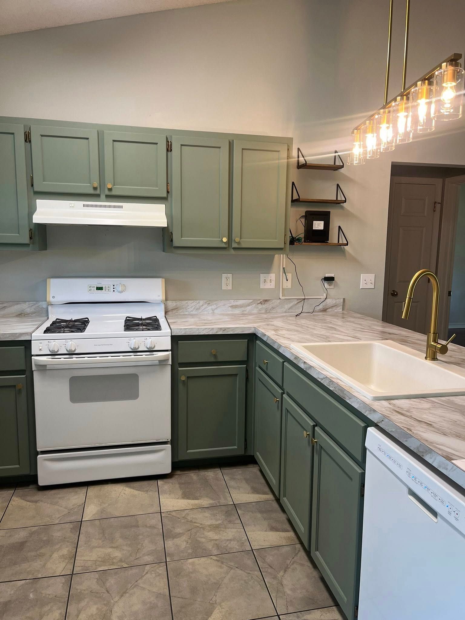 Green kitchen cabinets and white appliances in a well-lit space.