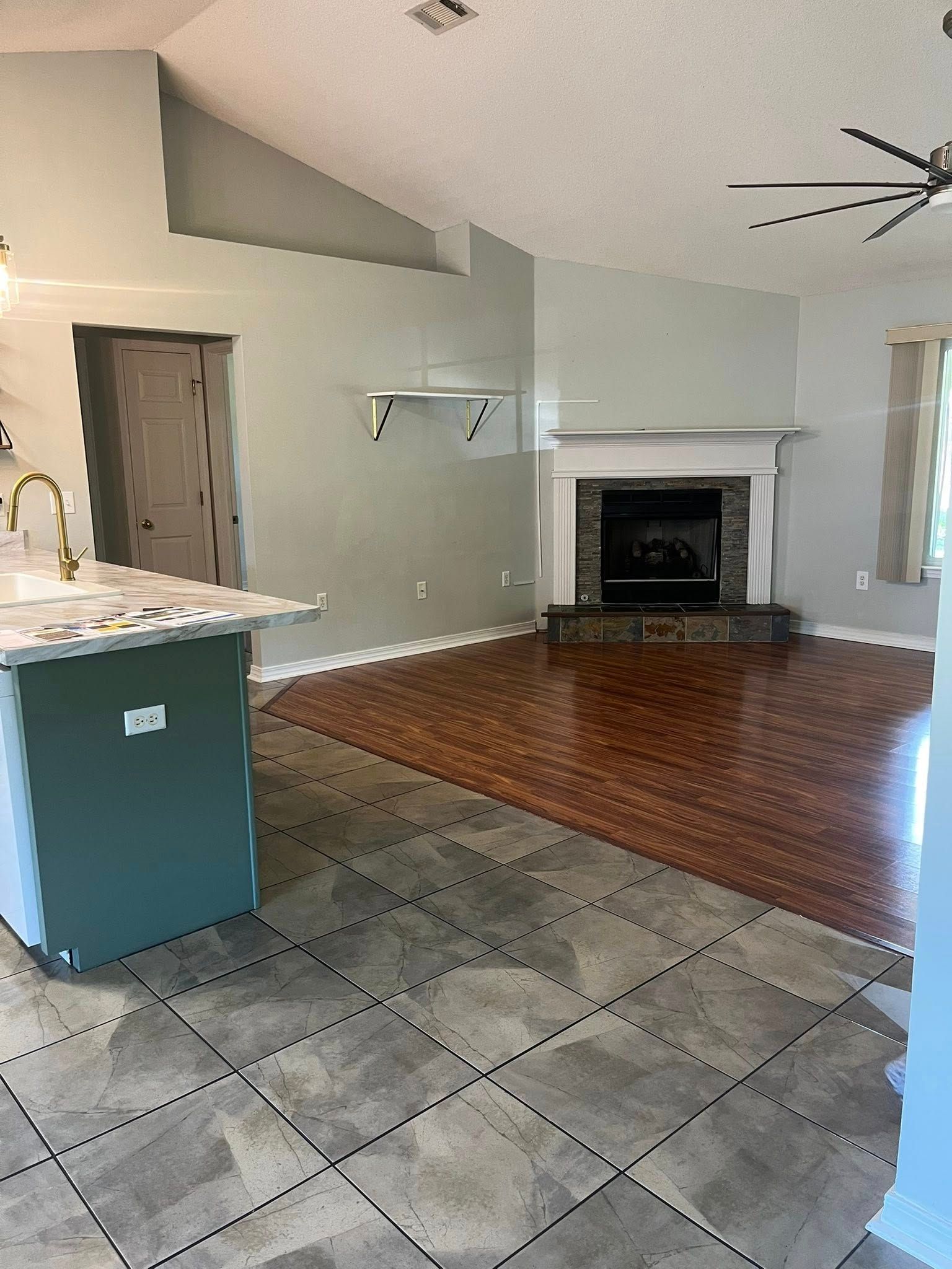 Living room with fireplace, kitchen island, hardwood floors, and tile floor.