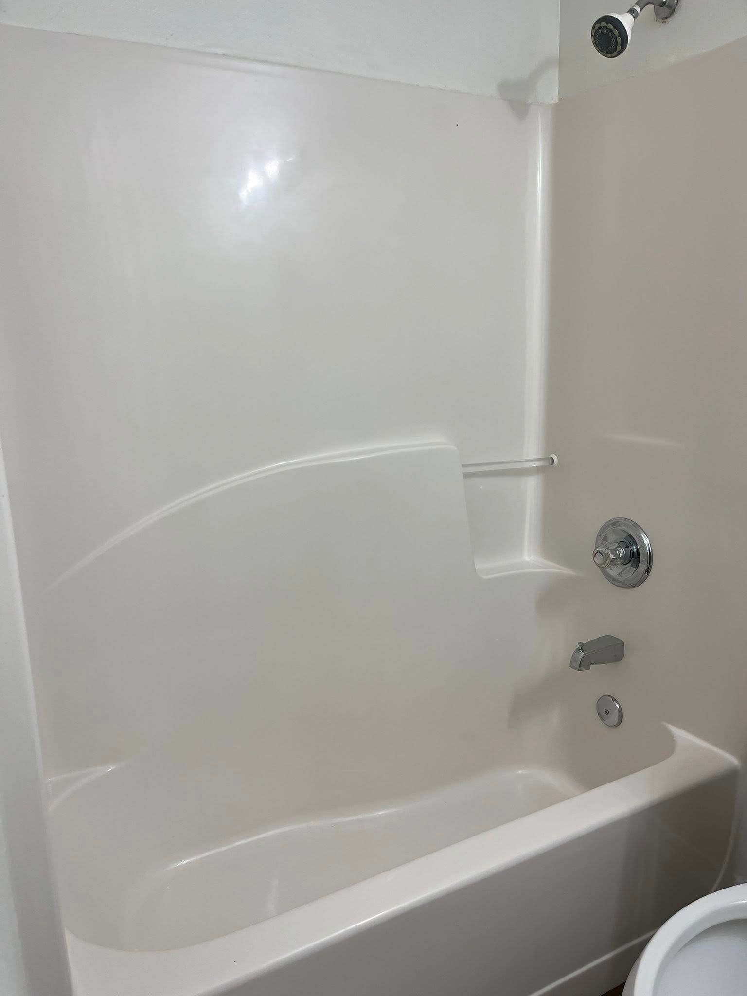 White bathtub and shower surround with chrome fixtures.
