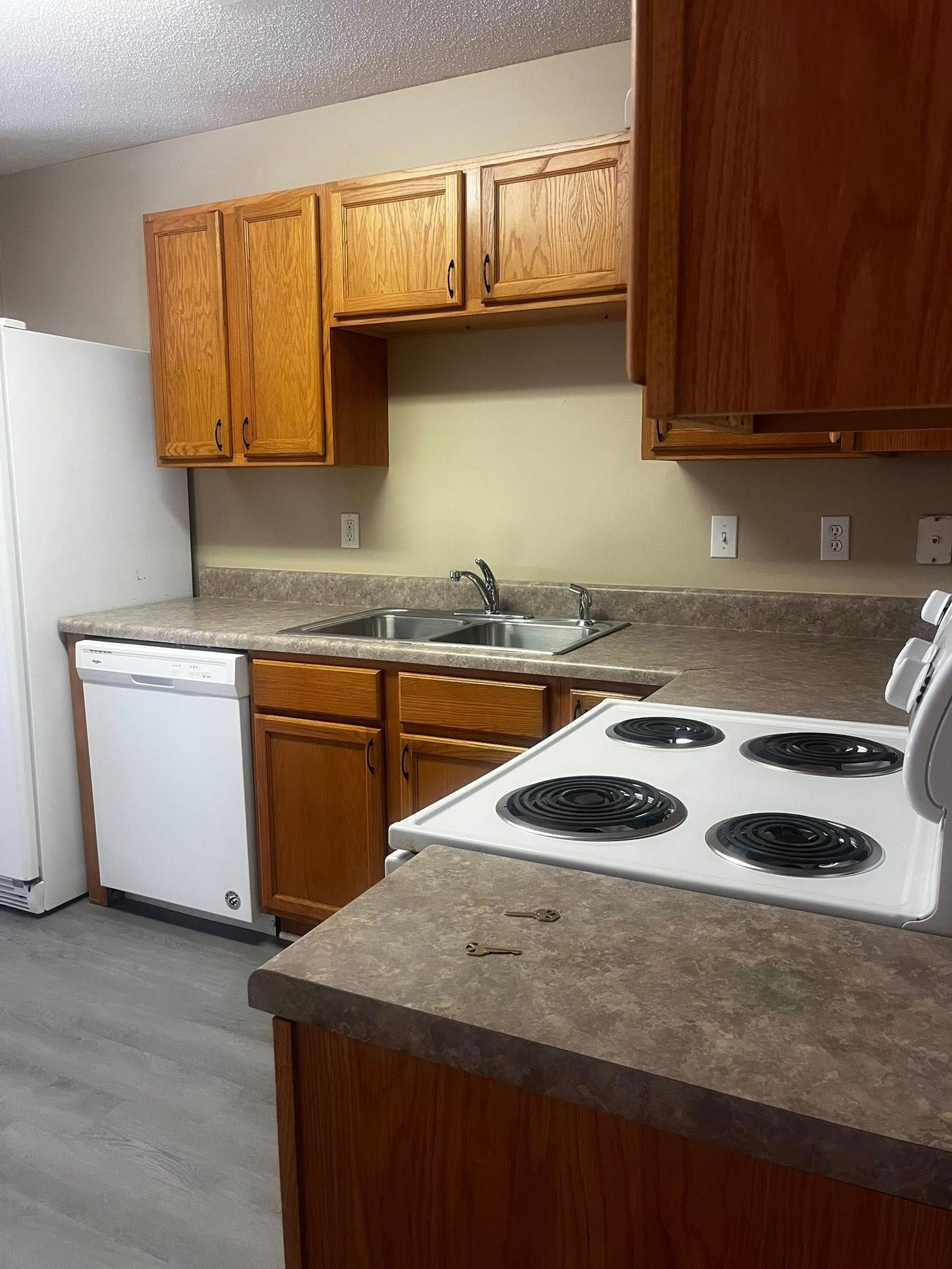Kitchen with wooden cabinets, white appliances, and gray countertops.
