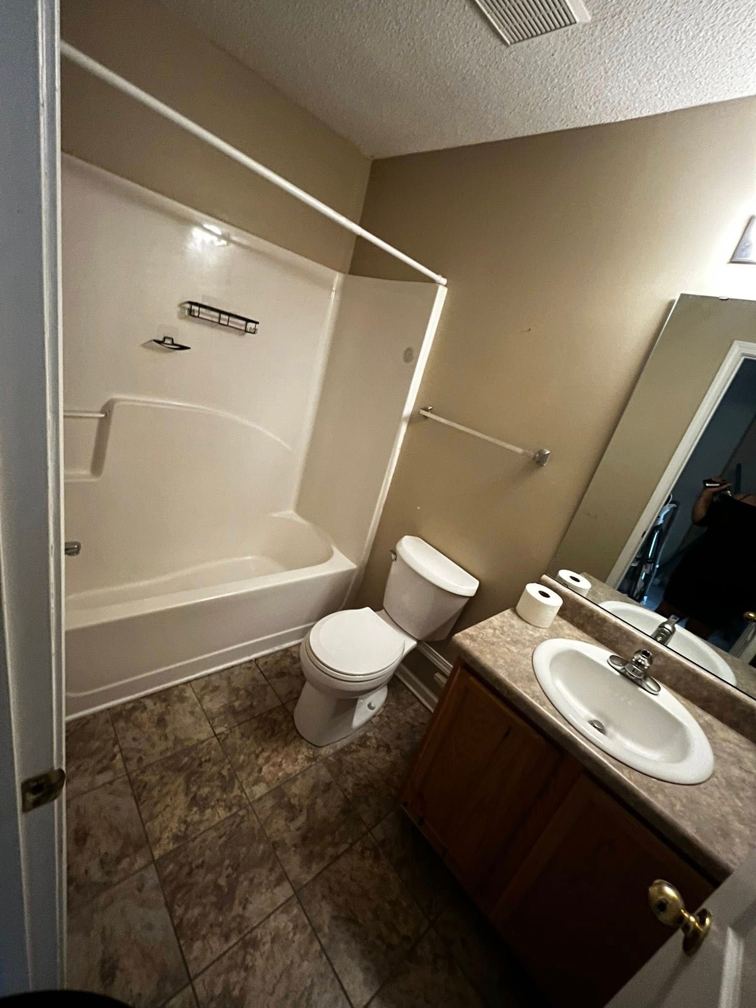 Bathroom with a white tub and toilet, sink, and neutral-colored walls.
