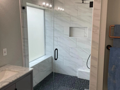 A bathroom with a walk in shower and a window.