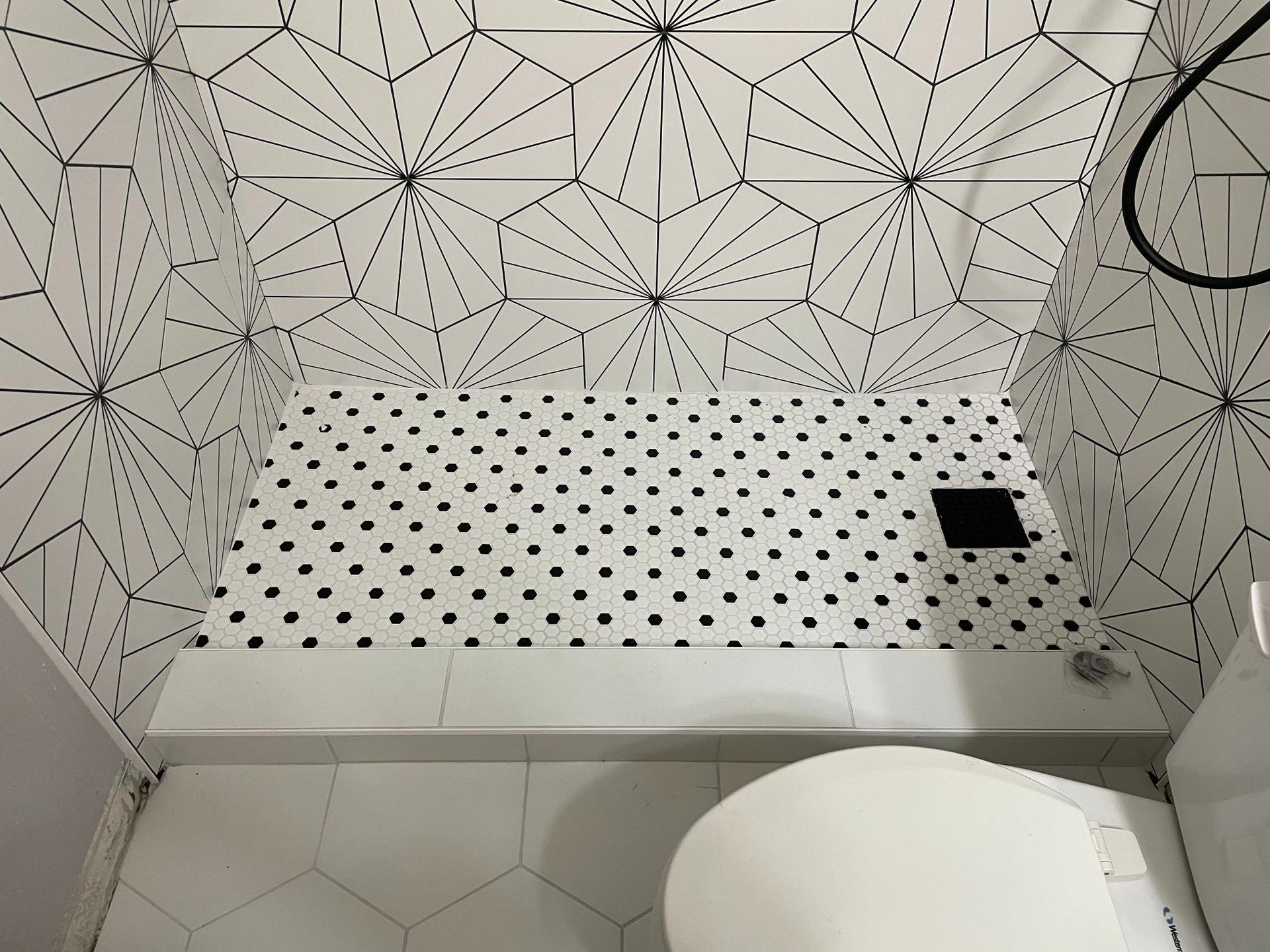 A bathroom with black and white tiles and a toilet.