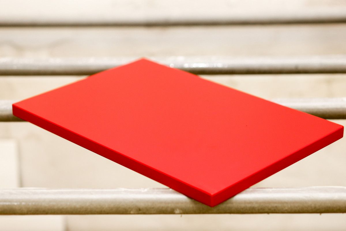 Ant metalinių laikiklių padėta raudonai dažyta medinė detalė