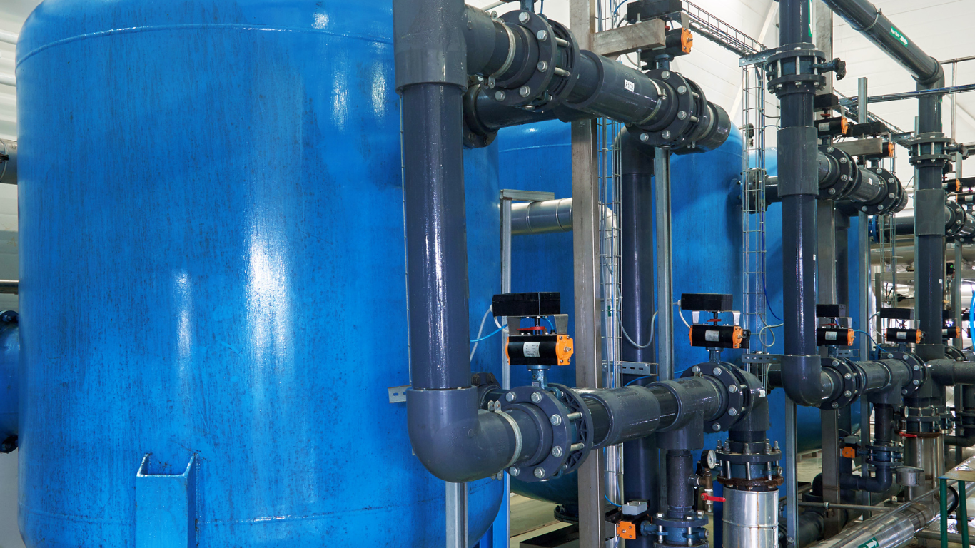 A row of blue tanks and pipes in a factory.
