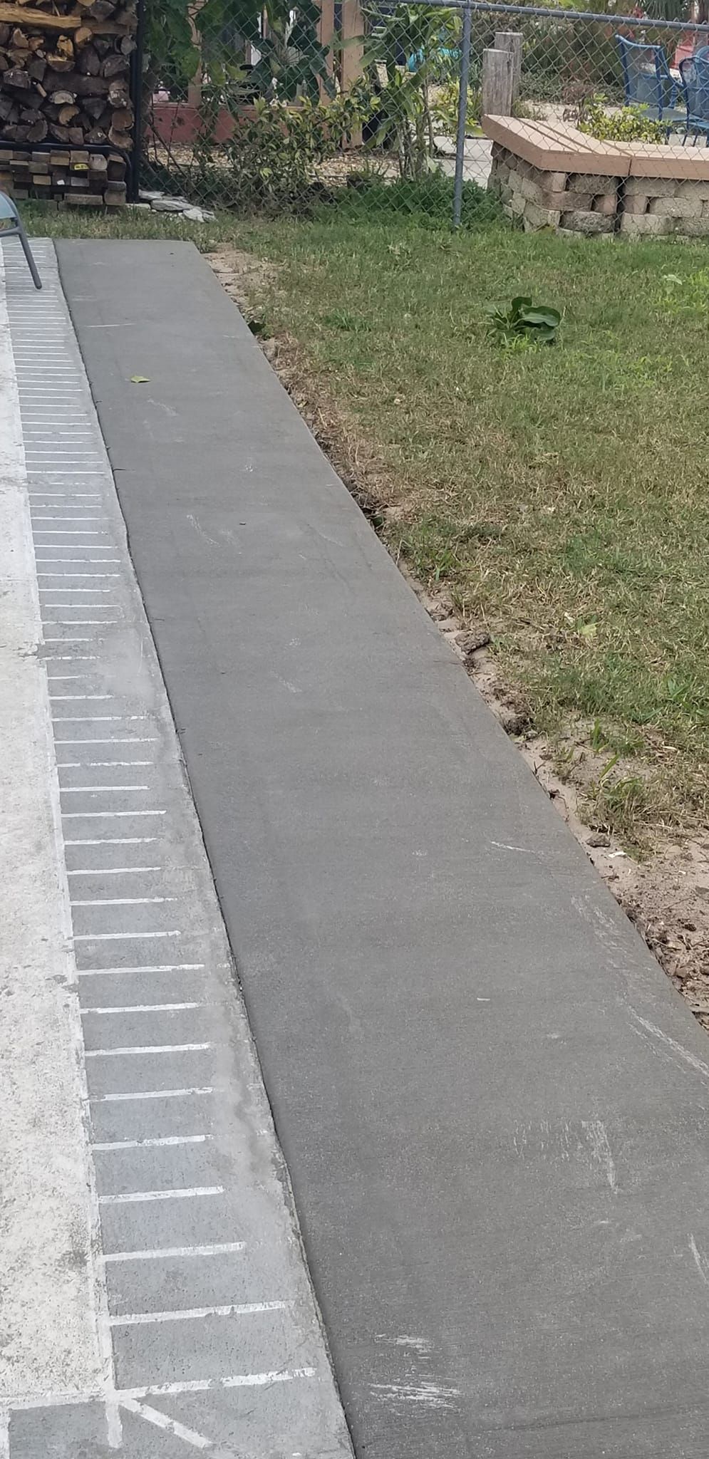 A narrow paved path next to grass. White lines are on the edge of the path.