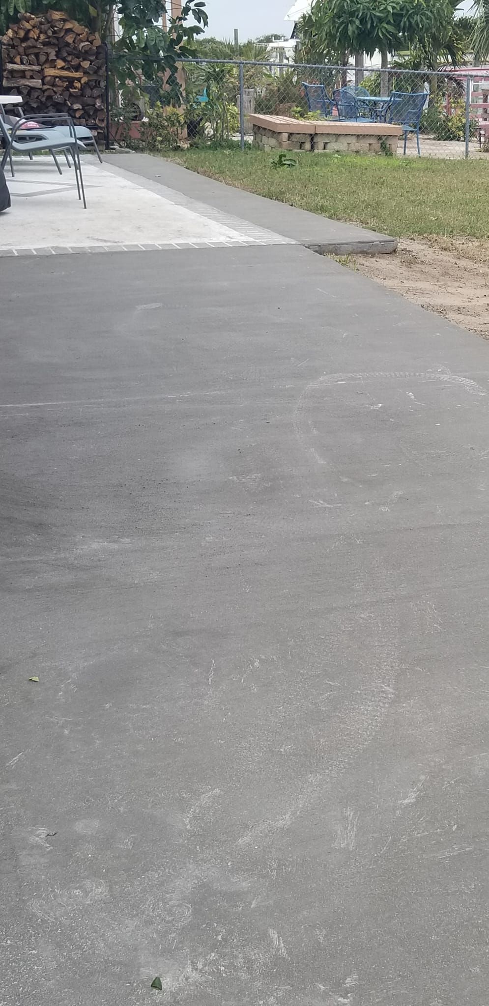 A paved pathway in a park, with trees, grass, and buildings visible in the background.