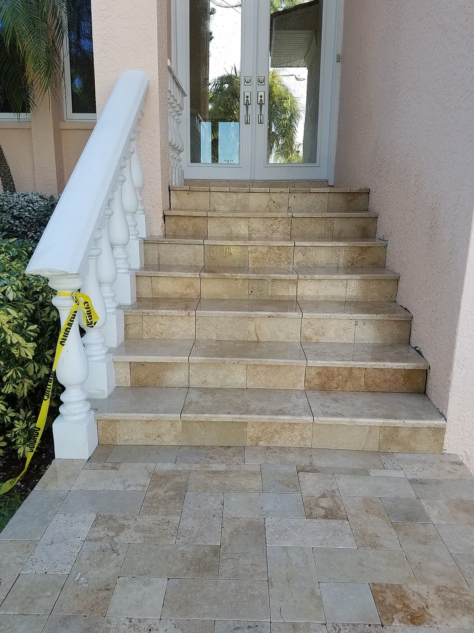 Stone steps leading to double glass doors; white balustrade on left.