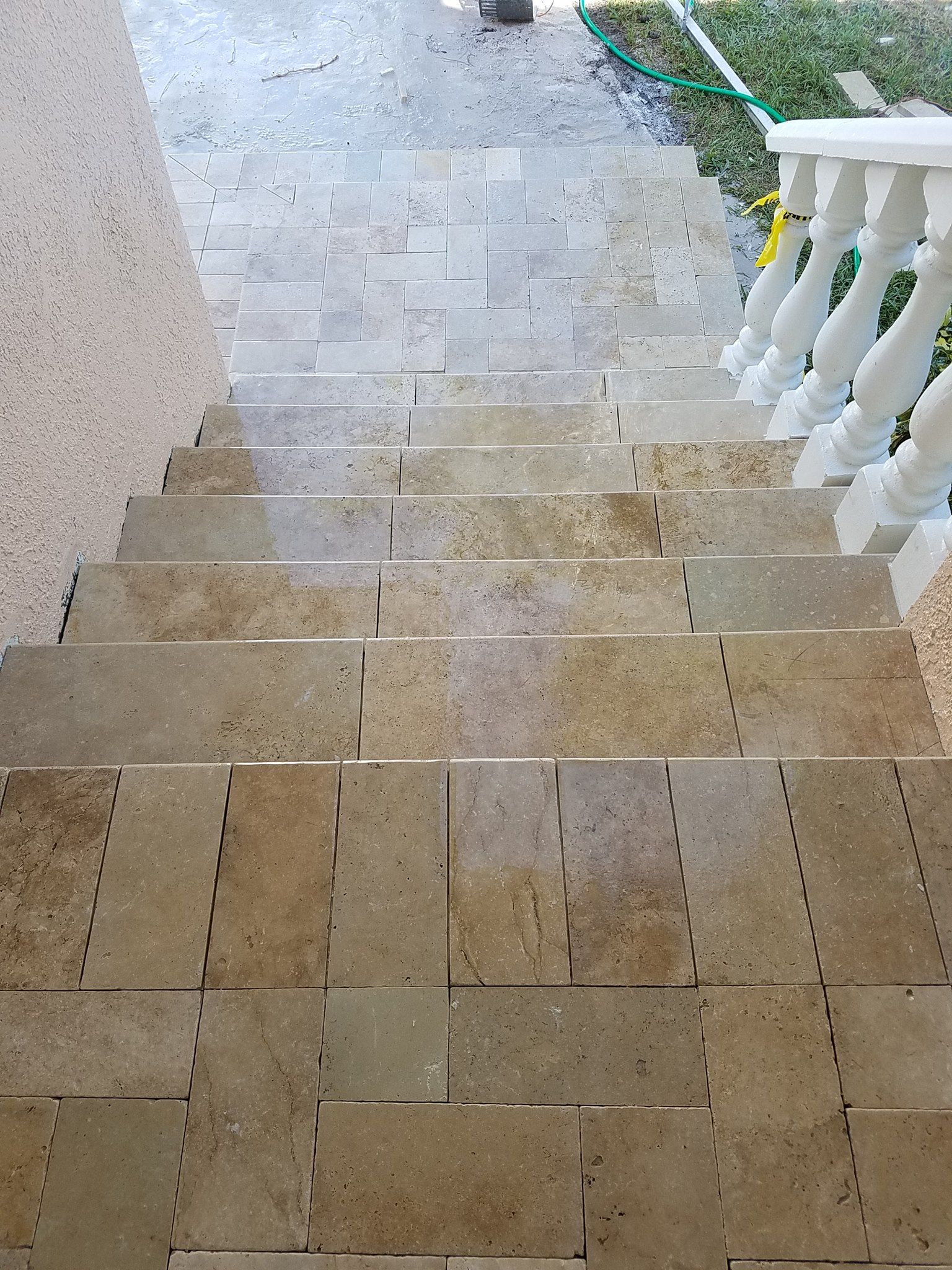 Stone steps leading downward, with a white railing on the right and stucco wall on the left.
