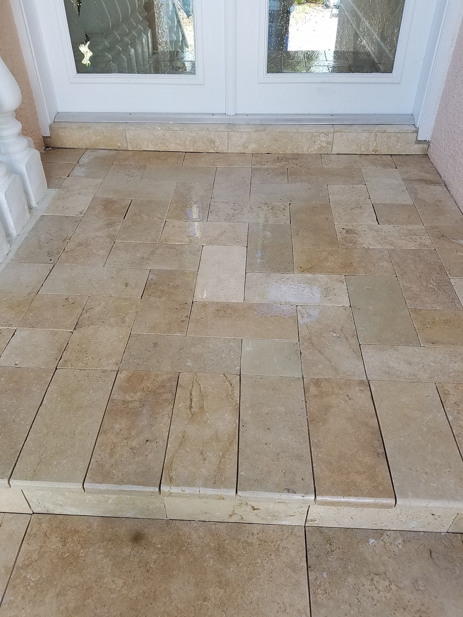 Beige tiled entryway leading to white French doors.