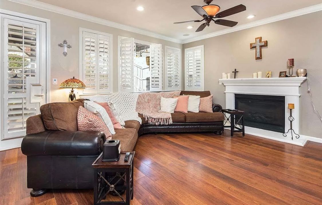 A living room with a couch , chair , fireplace and ceiling fan.