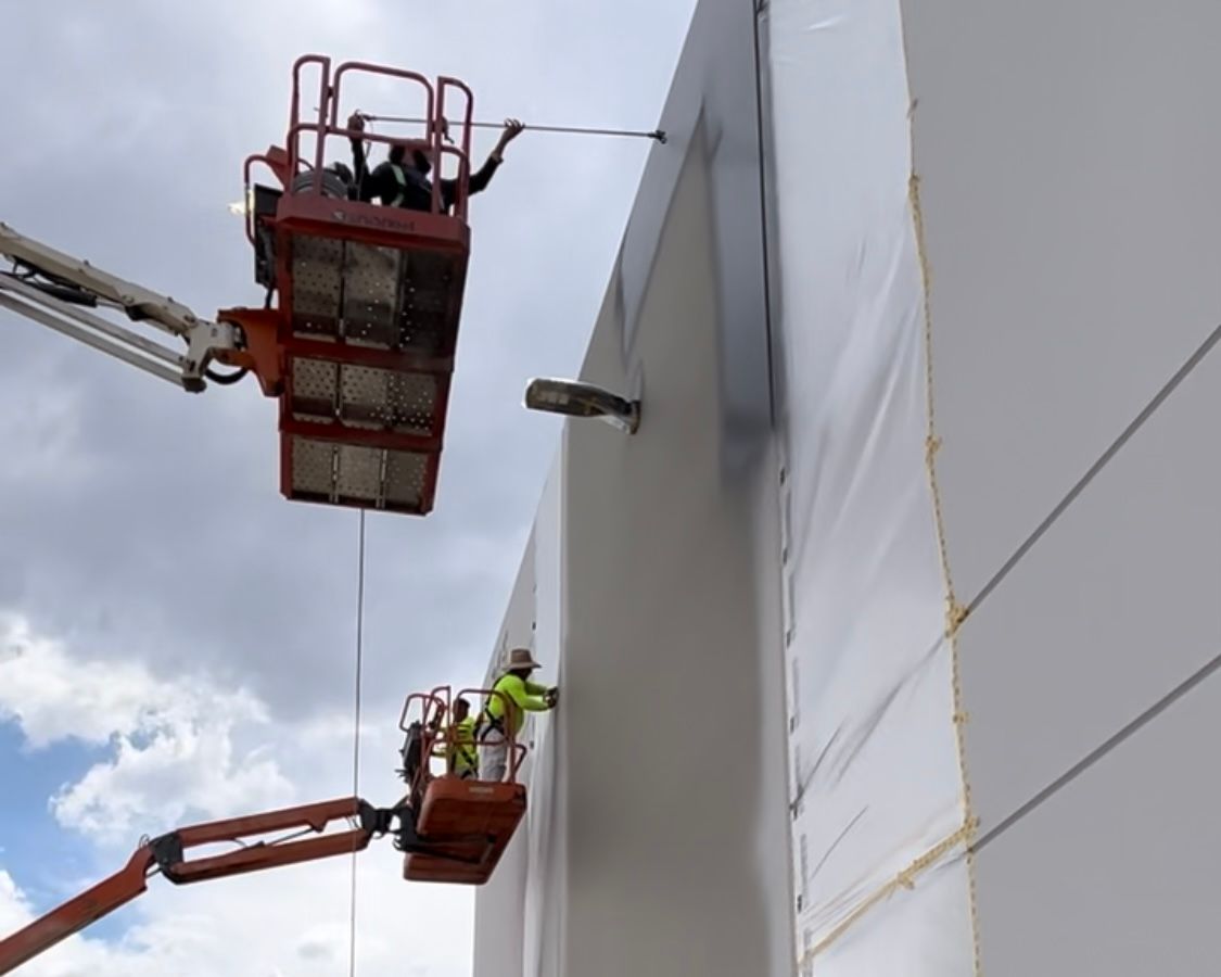 Two men are working on the side of a building