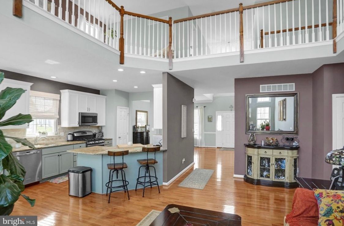 A living room with hardwood floors , a kitchen , and a balcony.