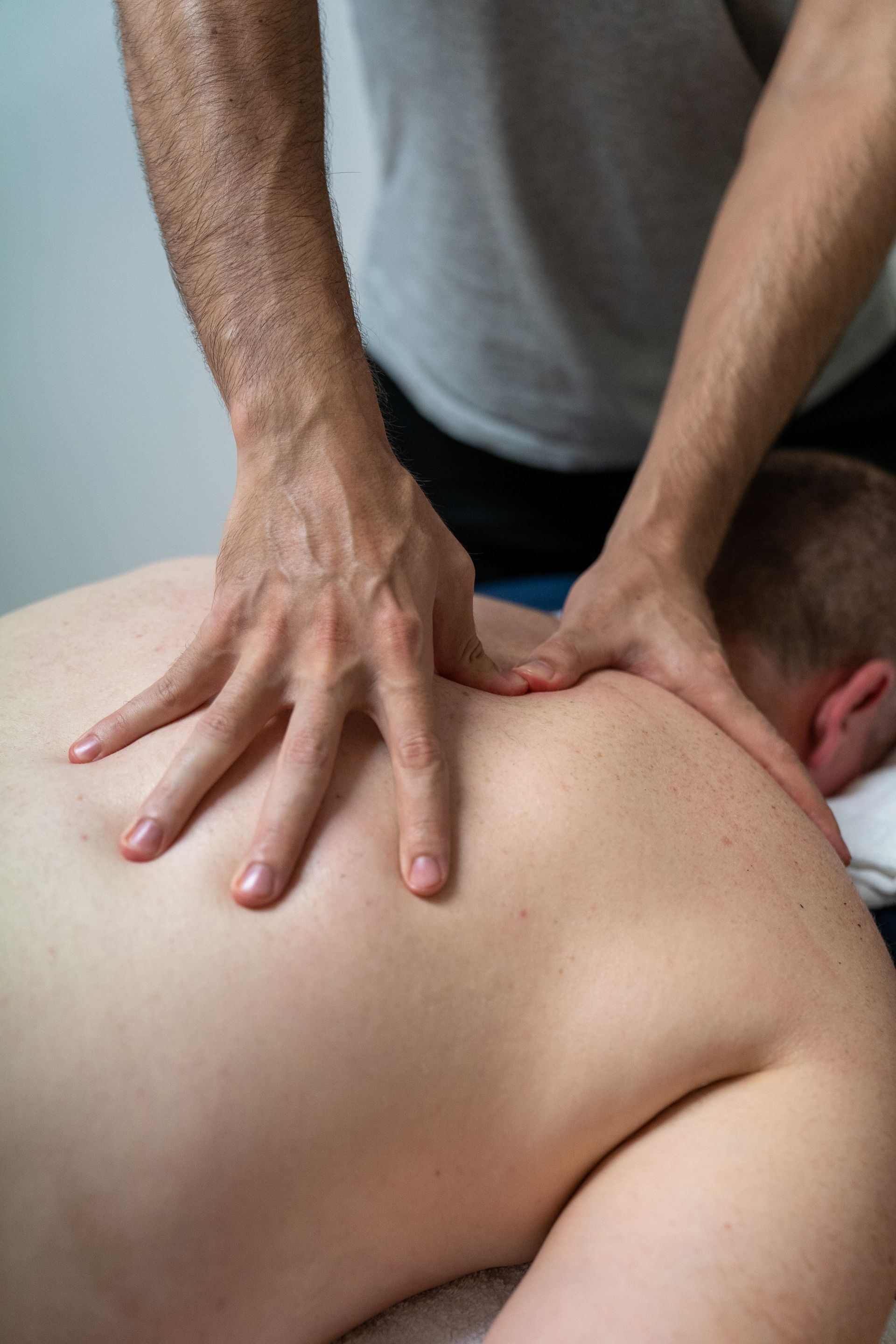 Person receiving a seated massage; a masseuse massages their back. Bright sunlight.