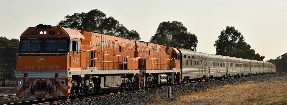 A train is going down the tracks in a field.