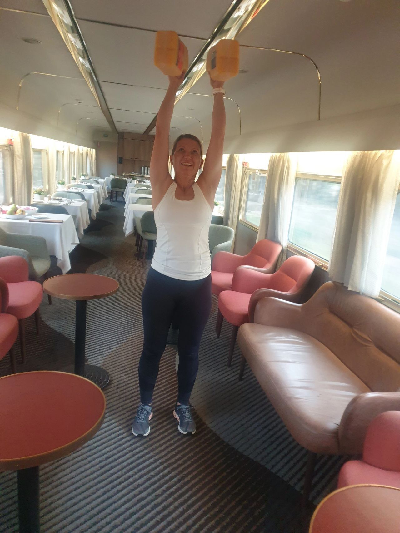 A woman is lifting a dumbbells on a train.