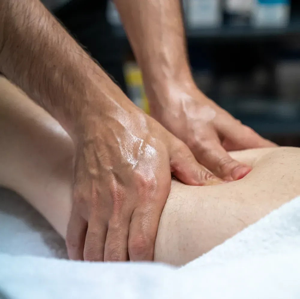 Hands giving a leg massage on a white towel, likely at a spa.