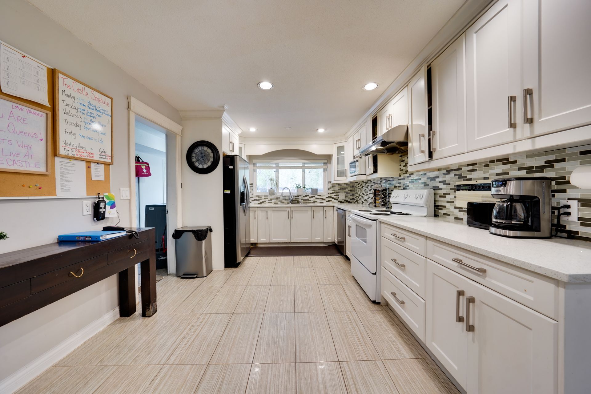 A kitchen with white cabinets , stainless steel appliances , and a coffee maker.