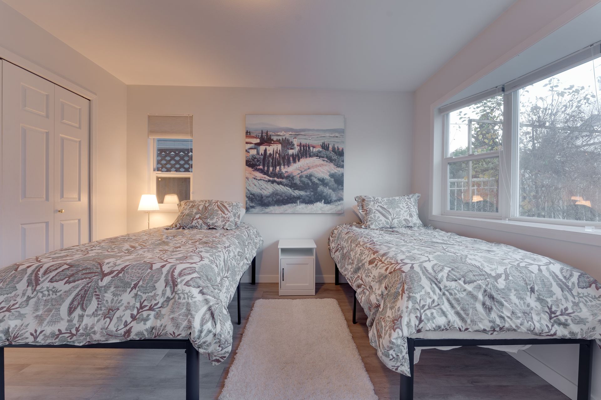 A bedroom with two beds and a painting on the wall
