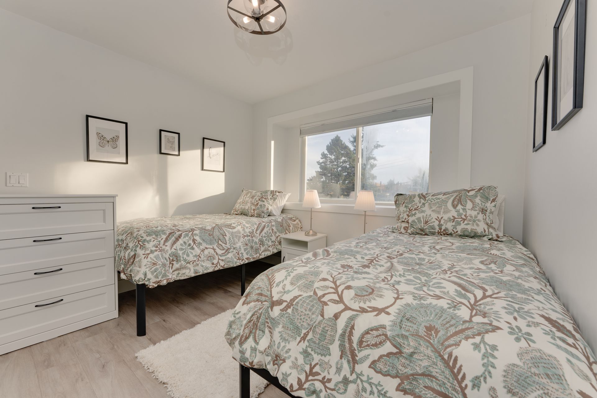 A bedroom with two beds , a dresser and a window.