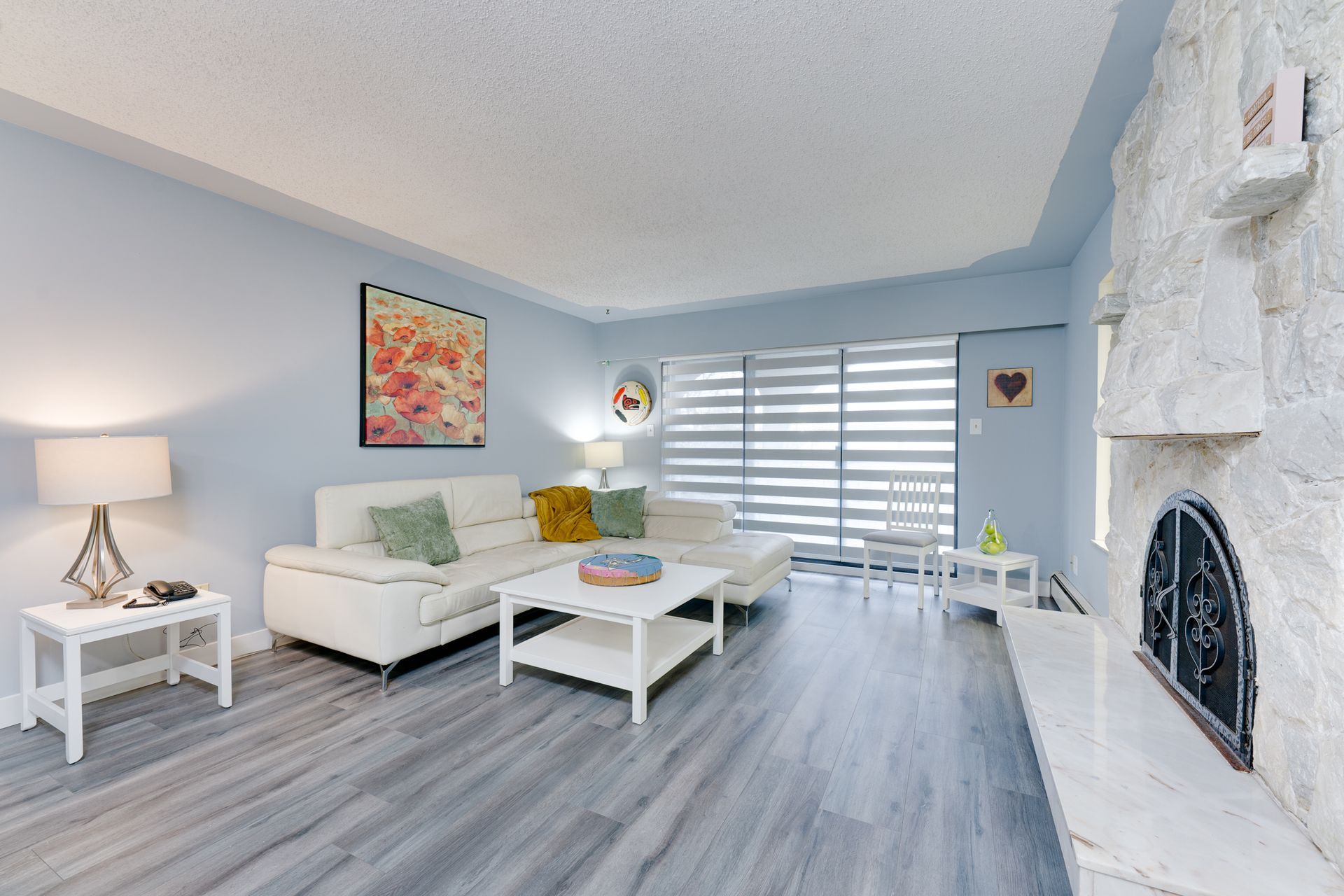 A living room with a couch , coffee table , fireplace and sliding glass doors.
