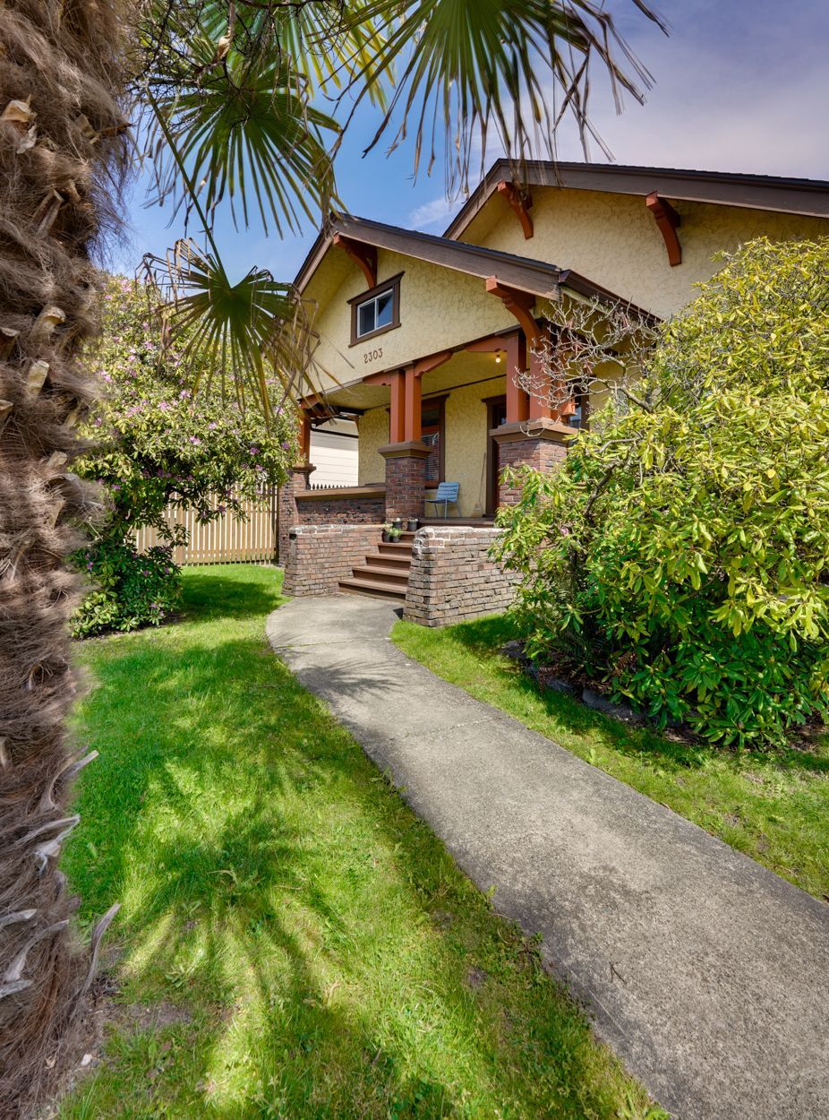 A house with a walkway leading to it and a palm tree in front of it.