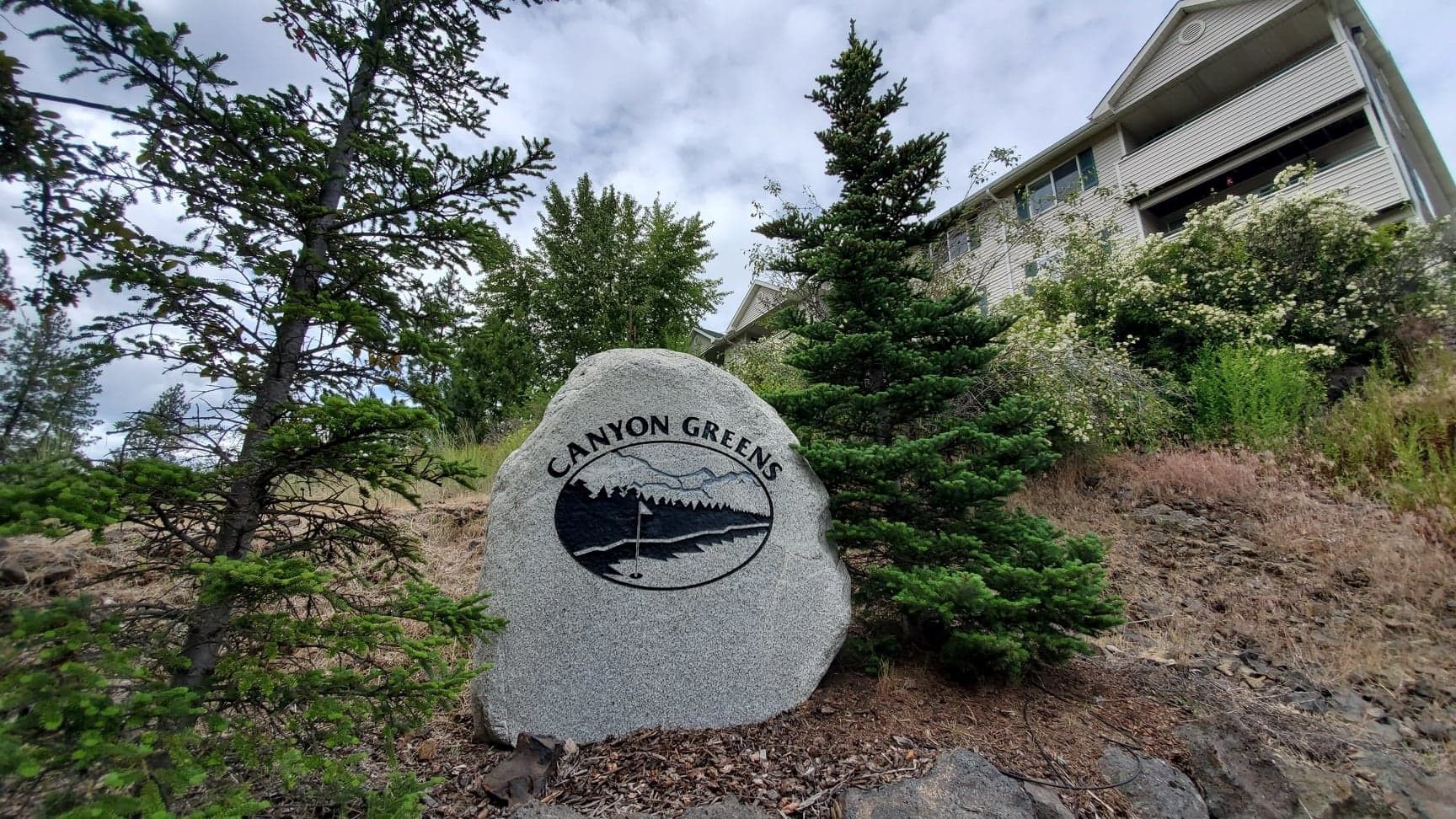 A large rock with the word cannon on it is in front of a house.
