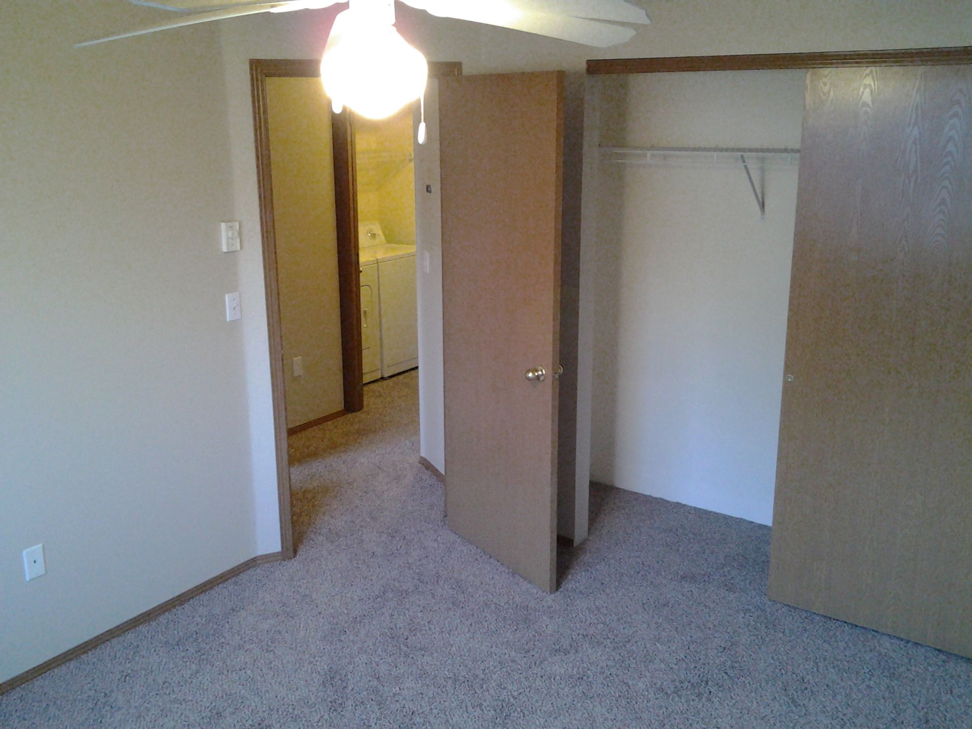 An empty bedroom with a ceiling fan and a closet