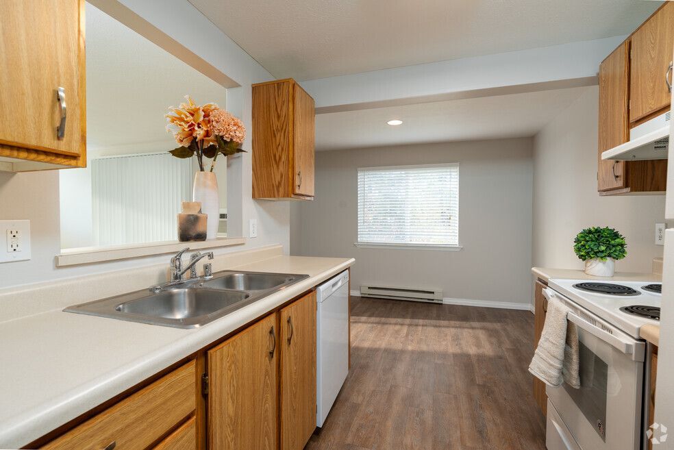 A kitchen with two sinks , a stove , a dishwasher , and a window.