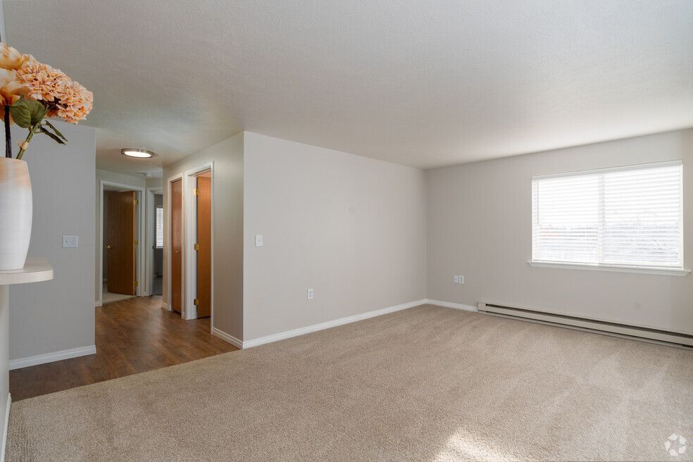 An empty living room with a vase of flowers on a shelf.