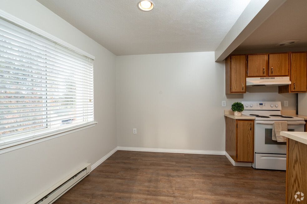 An empty kitchen with wooden cabinets , a stove , and a window.
