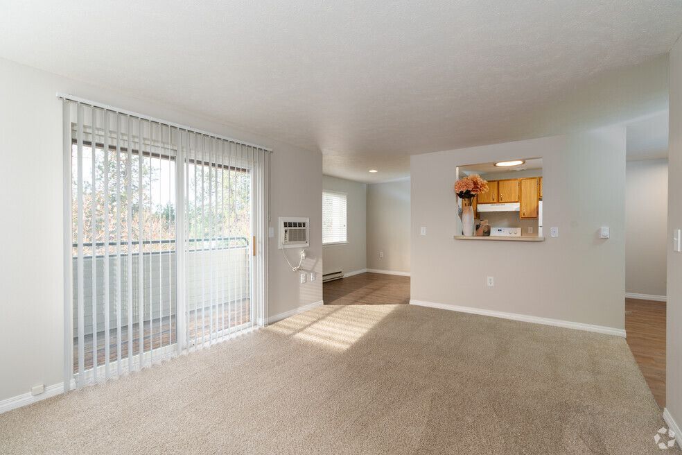 An empty living room with sliding glass doors leading to a balcony.