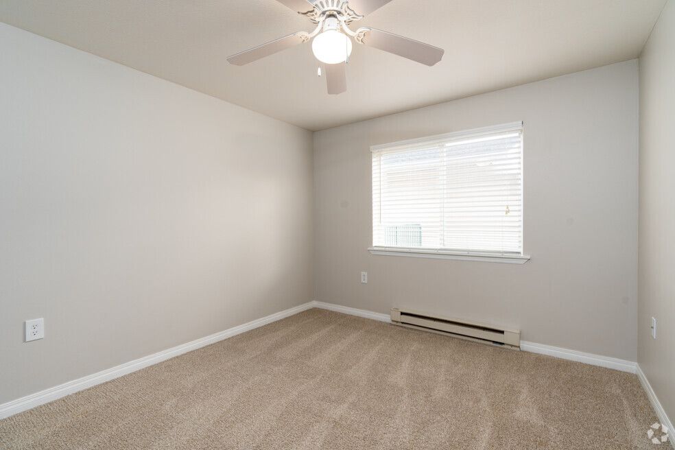 An empty bedroom with a ceiling fan and a window.