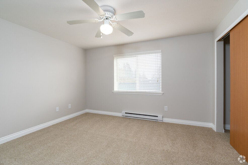 An empty bedroom with a ceiling fan and a window.
