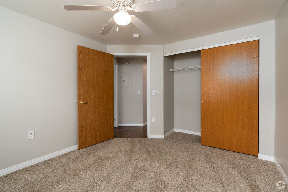 An empty bedroom with a ceiling fan and two closets.