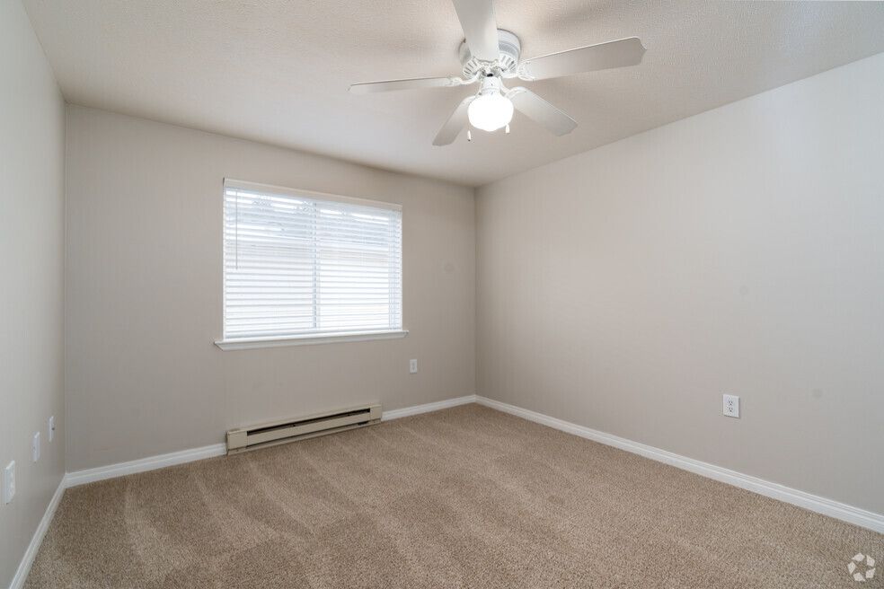 An empty bedroom with a ceiling fan and a window.