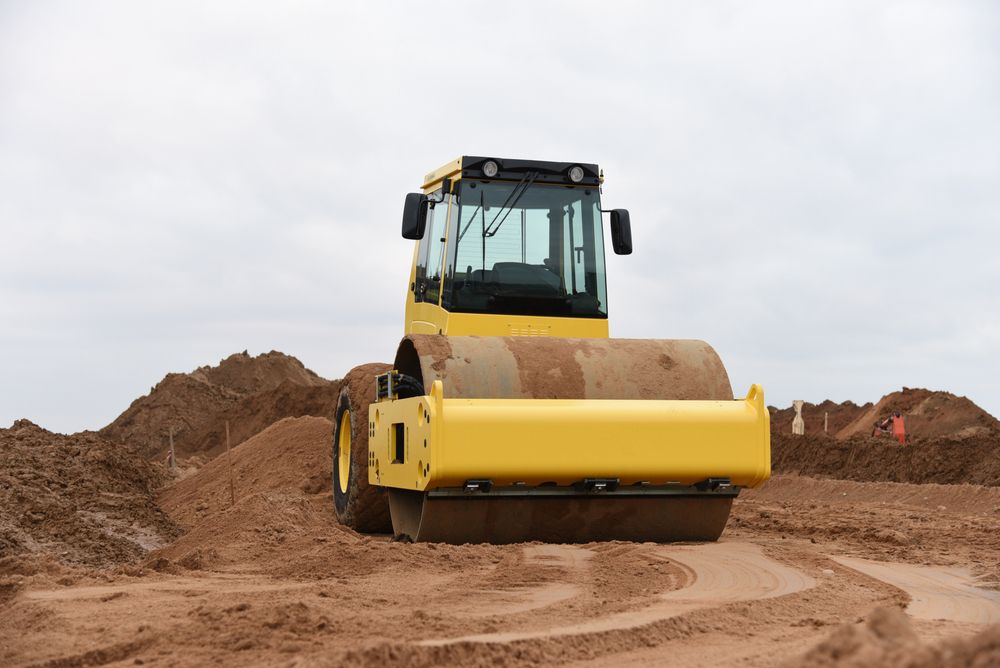 A Bright Yellow Soil Compactor Driving on a Construction Site — Environment Restoration Solutions in Coffs Harbour, NSW