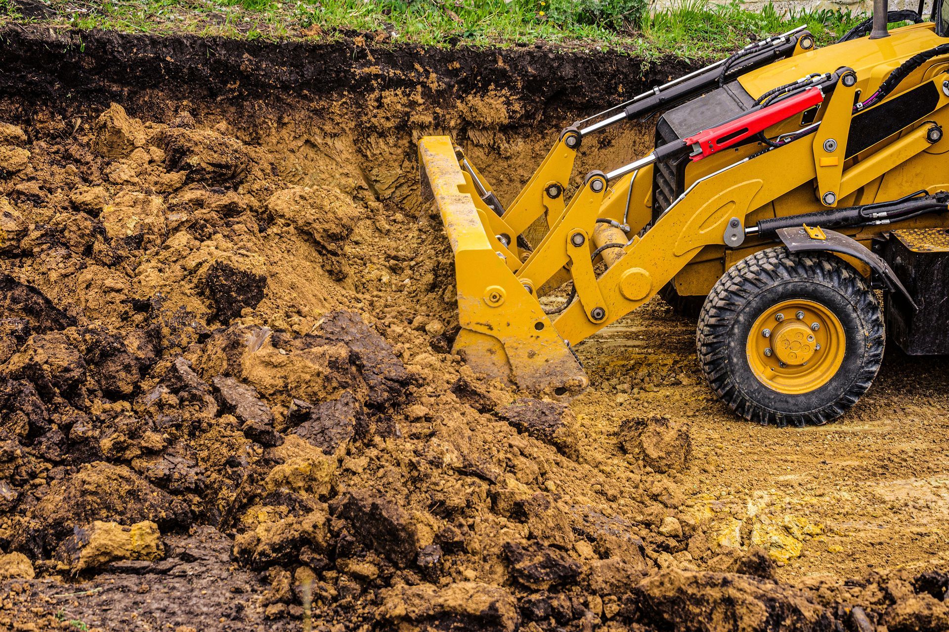 A Yellow Tractor-loader Pushes a Large Pile of Earth — Environment Restoration Solutions in Coffs Harbour, NSW