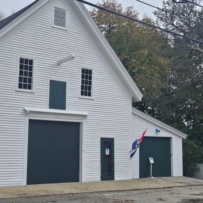 White building with two large dark green garage doors and an American flag.