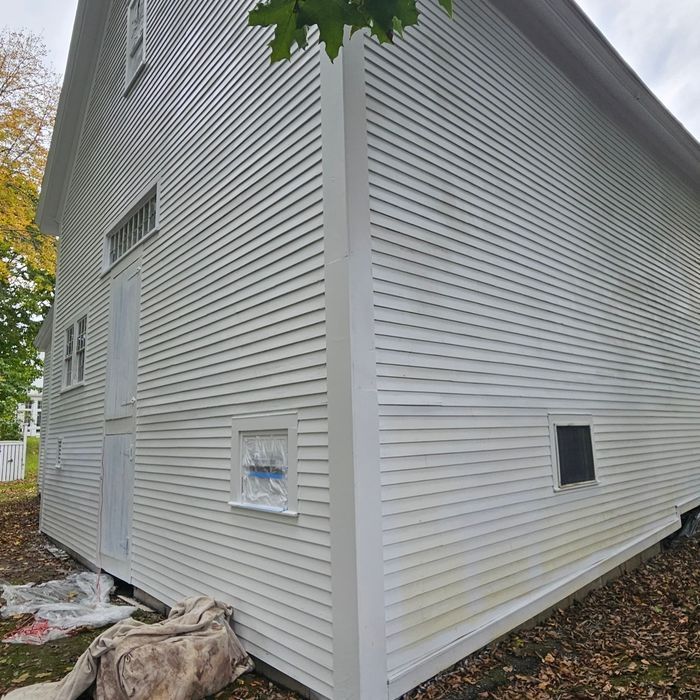 White barn with clapboard siding and a few windows. The barn is in an outdoor setting.