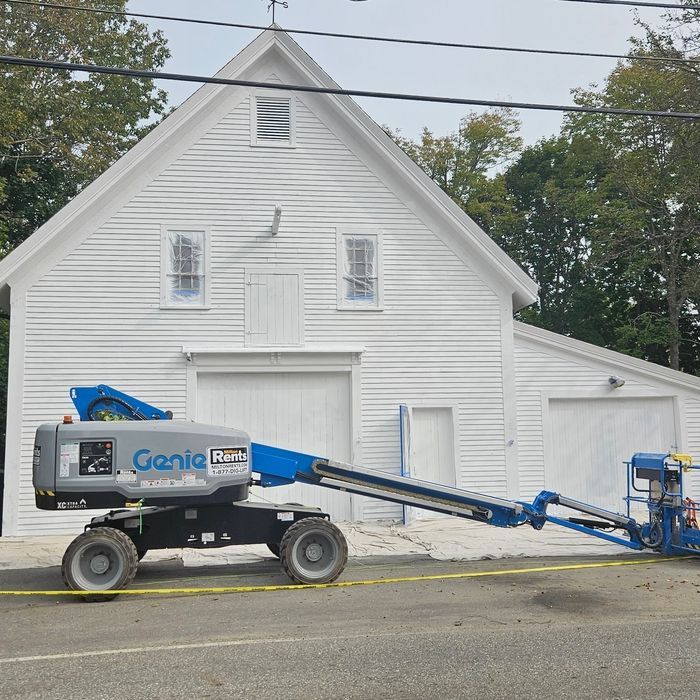 A white building with a blue lift in front, under a cloudy sky.