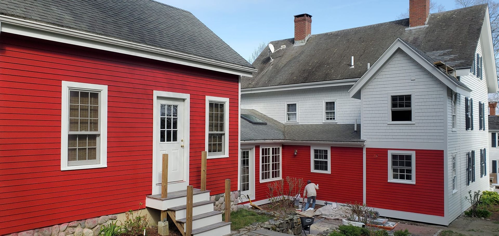 Red and white buildings with gray roofs and a person working outside.